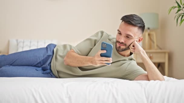 Jonge Spaanse Man Met Behulp Van Smartphone Liggend Bed Slaapkamer — Stockvideo