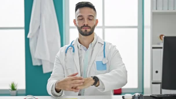 Joven Médico Hispano Sentado Mesa Con Expresión Seria Apuntando Observar — Vídeo de stock