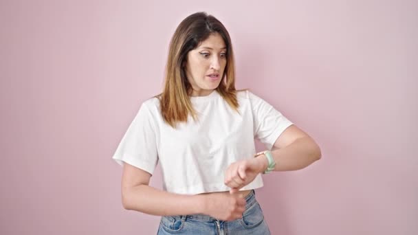 Mujer Rubia Joven Mirando Reloj Con Expresión Nerviosa Sobre Fondo — Vídeos de Stock