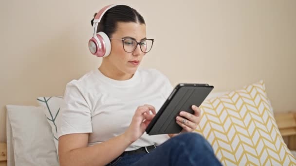 Fiatal Gyönyörű Spanyol Érintőpadot Használ Ágyon Ülve Fejhallgatót Visel Hálószobában — Stock videók