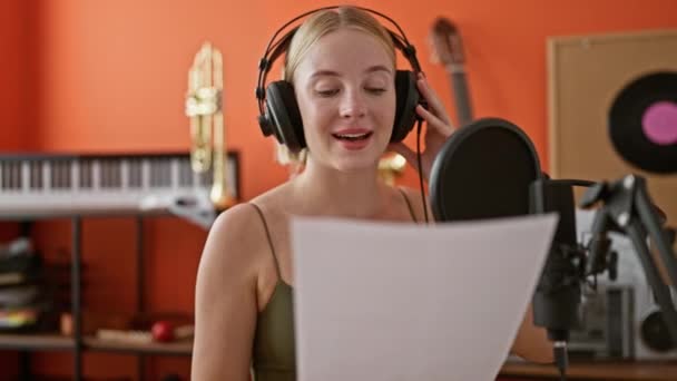 年轻的金发女音乐家在音乐演播室里自信地唱着歌 — 图库视频影像