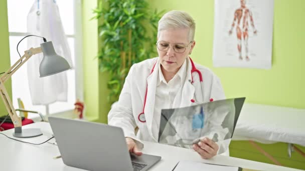 Medelålders Gråhårig Kvinna Läkare Tittar Röntgen Med Laptop Kliniken — Stockvideo