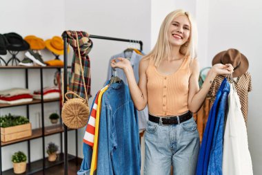 Elbise mağazasında gülümseyen genç sarışın kadın müşteri.