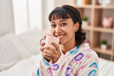 Genç, güzel, İspanyol bir kadın. Yatak odasında bir fincan kahve içiyor.