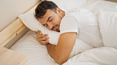 Genç İspanyol adam yastığa sarılıyor. Yatak odasında uyuyor.
