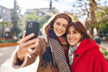 Two women mother and daughter make selfie by smartphone at park