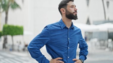 Latin kökenli genç adam ciddi bir ifadeyle sokağa bakıyor.