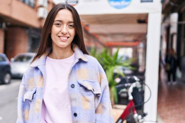 Kahve dükkanının terasında kendine güvenen güzel İspanyol kadın gülümsüyor.