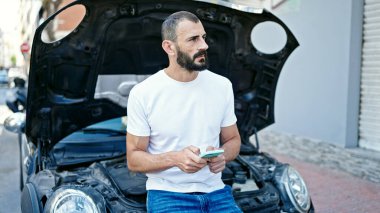 Genç İspanyol adam araba arızası için akıllı telefondan sigorta ile mesajlaşıyor.