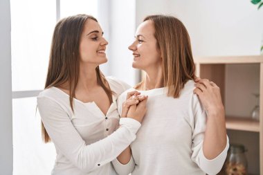 Two women mother and daughter hugging each other at home