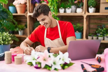 Çiçekçide dizüstü bilgisayar kullanan İspanyol bir çiçekçi.