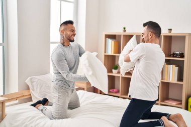 Two men couple fighting with pillows at bedroom