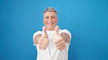 İzole edilmiş mavi arka planda gülümseyen beyaz bir genç.