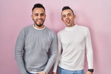 Pembe arka planda duran eşcinsel çift komik bir ifadeyle dillerini dışarı çıkarıyorlar. duygu kavramı. 
