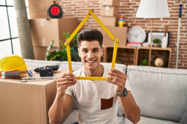 Genç İspanyol bir adam yeni evine mutlu ve havalı bir gülümsemeyle taşınıyor. diş gösterme. 