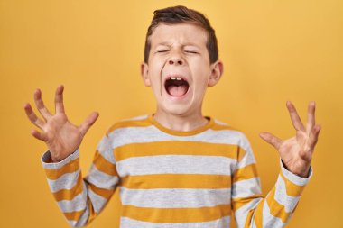 Sarı arka planda duran genç beyaz çocuk, başarı için deli ve çılgınlığı kutluyor. Kolları havada ve gözleri kapalı, heyecanlı bir şekilde bağırıyor. Kazanan konsept 