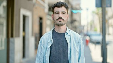 Sokakta ciddi bir ifadeyle duran İspanyol genç adam.