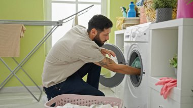 Çamaşırhanede çamaşır yıkayan İspanyol genç adam.