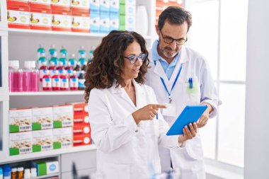 Eczanede çalışan erkek ve kadın eczacılar dokunmatik ped kullanıyorlar.