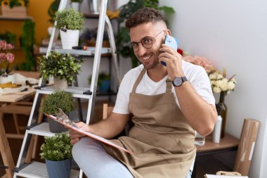 Çiçekçide akıllı telefondan konuşan genç İspanyol çiçekçi.