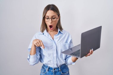 Bilgisayarla çalışan genç bir kadın parmaklarıyla aşağıya işaret ederek reklamını, şaşırmış yüzünü ve ağzını açıyor. 