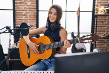 Müzik stüdyosunda klasik gitar çalan sevimli bir müzisyen kız.