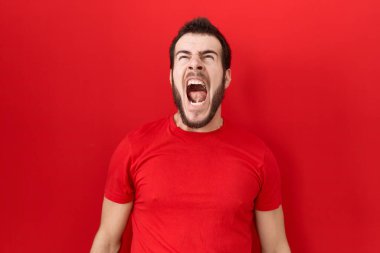 Genç, İspanyol asıllı, normal kırmızı t-shirt giyen sinirli ve kızgın çığlık atan sinirli, öfkeyle bağıran bir adam. öfke ve agresif konsept. 