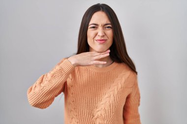 Genç esmer kadın beyaz arka planda duruyor. Bıçak niyetine boğazını kesiyor. Saldırganlığı şiddetle tehdit ediyor. 