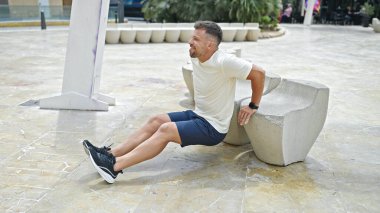 Genç adam parkta şınav çekiyor.