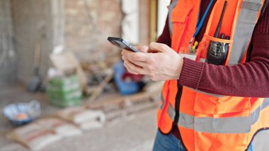 İnşaat alanında akıllı telefon kullanan genç İspanyol müteahhit.