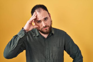Ayrıca sarı arka planda dikilen sakallı, iri yarı Latin bir adam. Alnındaki bir sorun yüzünden endişeli ve stresli. Kriz için endişeli. 