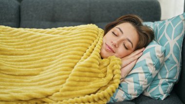 Young beautiful hispanic woman lying on sofa sleeping at home