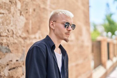 Sokakta ciddi bir ifadeyle duran beyaz bir genç.