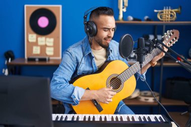 Genç İspanyol sanatçı müzik stüdyosunda klasik gitar çalarak şarkı söylüyor.