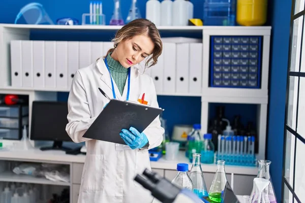 Young woman scientist writing report at laboratory