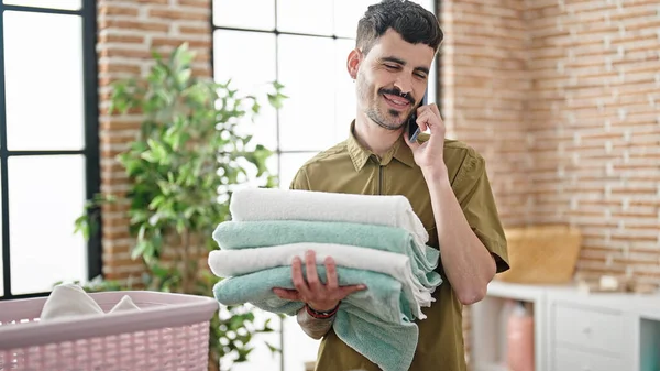 Genç Spanyol Adam Çamaşır Odasında Elinde Katlanmış Havlularla Akıllı Telefondan — Stok fotoğraf