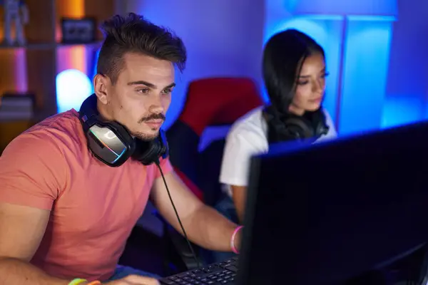 Man and woman streamers playing video game using computer at gaming room