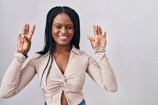非洲女人头上戴着辫子 站在白色的背景上 用8号手指指尖 面带微笑 自信而快乐 — 图库照片