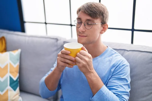Νεαρός Καυκάσιος Άντρας Μυρίζει Καφέ Καθισμένος Στον Καναπέ Στο Σπίτι — Φωτογραφία Αρχείου