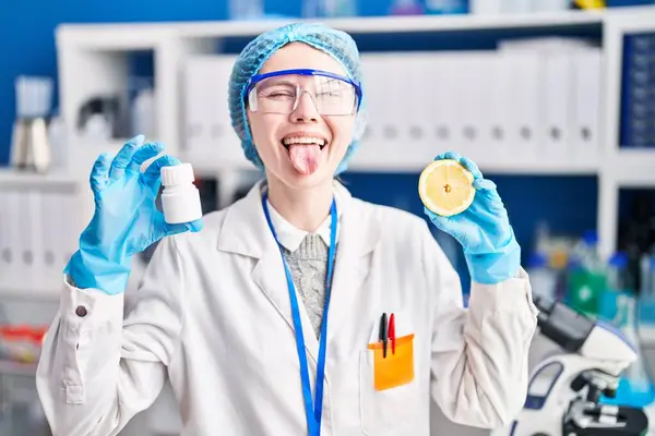 面白い表現で幸せな舌を突き刺す科学者の実験室で働く美しい女性 — ストック写真