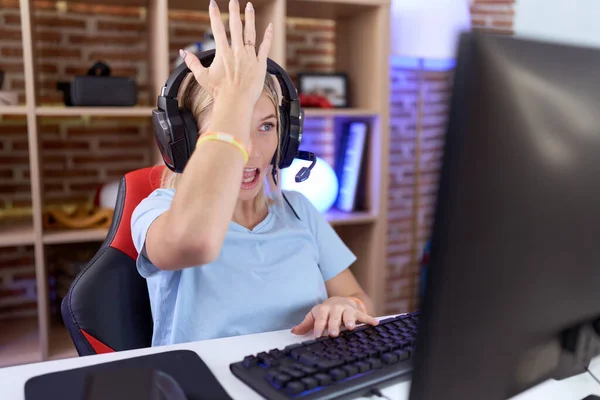 Νεαρή Καυκάσια Γυναίκα Που Παίζει Βιντεοπαιχνίδια Φορώντας Ακουστικά Έκπληκτη Χέρι — Φωτογραφία Αρχείου