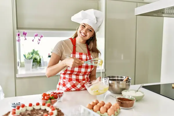 Genç, güzel İspanyol kadın, gülümsüyor. Mutfakta yumurta karıştırıyor.