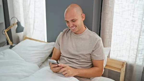 Young Hispanic Man Using Smartphone Sitting Bed Bedroom — Stockfoto