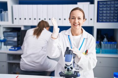 Gaddarlık içermeyen laboratuarda çalışan sarışın kadın zaferi mutlu bir gülümsemeyle kutluyor ve ellerini kaldırarak kazanan ifade ediyor. 