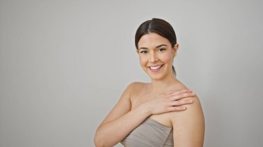 Genç, güzel, İspanyol bir kadın gülümsüyor. Kendine güvenen, omuzlarına dokunan, izole beyaz bir arka plan.