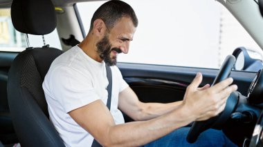 Young hispanic man smiling confident driving car at street