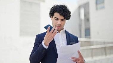 Genç Latin iş adamı akıllı telefon okuma belgesi ile sesli mesaj gönderiyor.