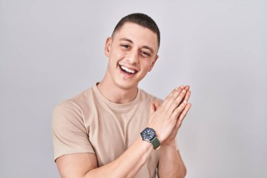Young man standing over isolated background clapping and applauding happy and joyful, smiling proud hands together 