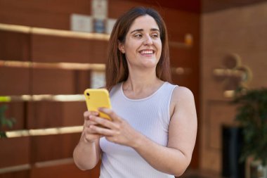 Sokakta akıllı telefon kullanan kendine güvenen genç bir kadın.