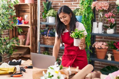 Çiçekçide dizüstü bilgisayar kullanan güzel İspanyol bir çiçekçi.